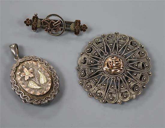 A Victorian silver yellow metal oval locket and two other brooches.